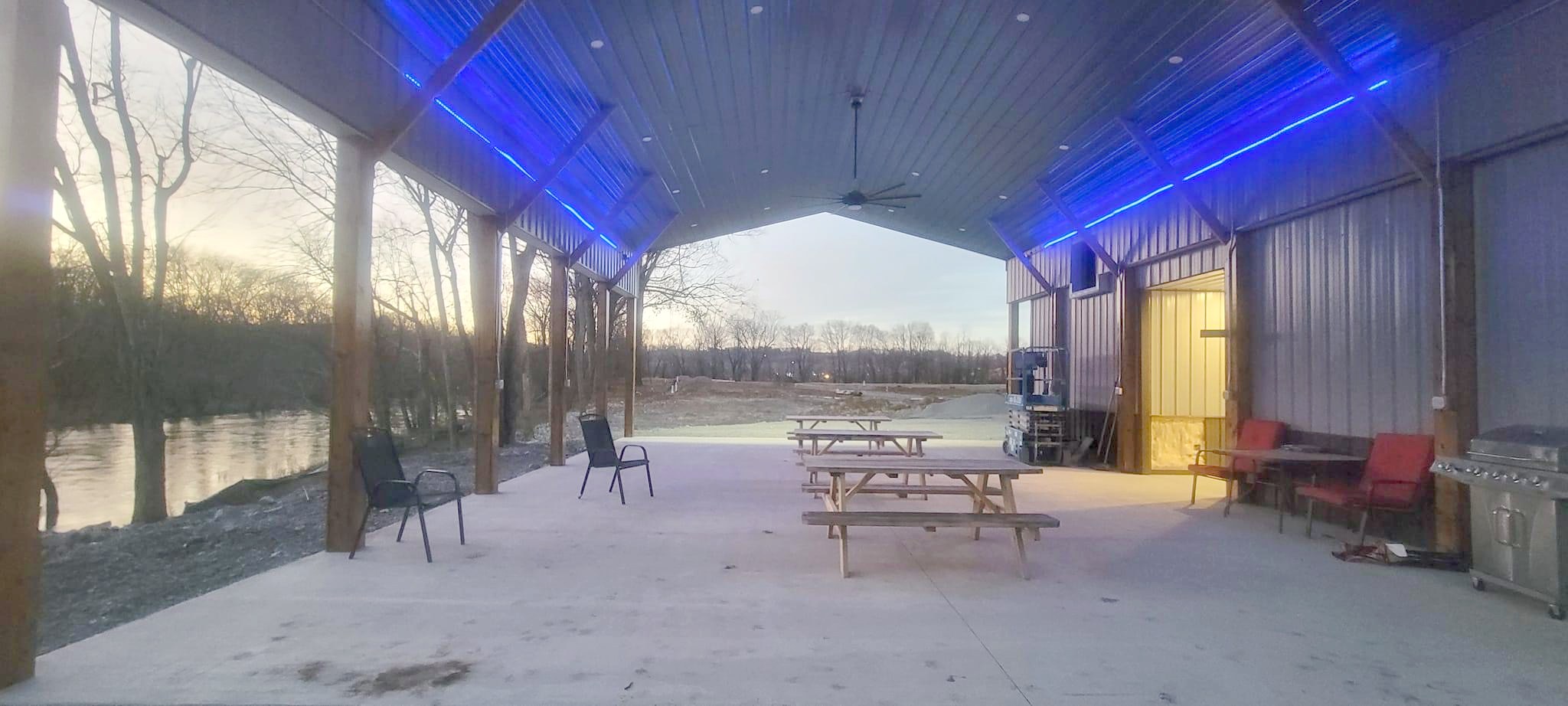Riverside pavilion at Paddle Trail with picnic tables and grill in morning light